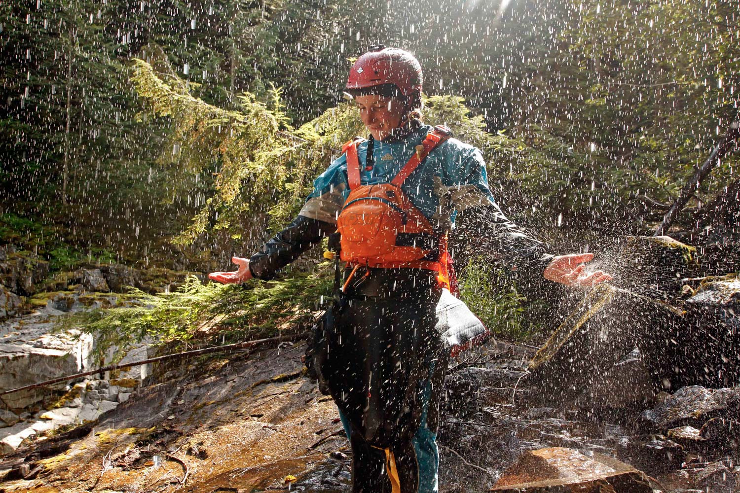 Louise, a top slalom kayaker who later converted to extreme whitewater kayaking, stands in a waterfall.